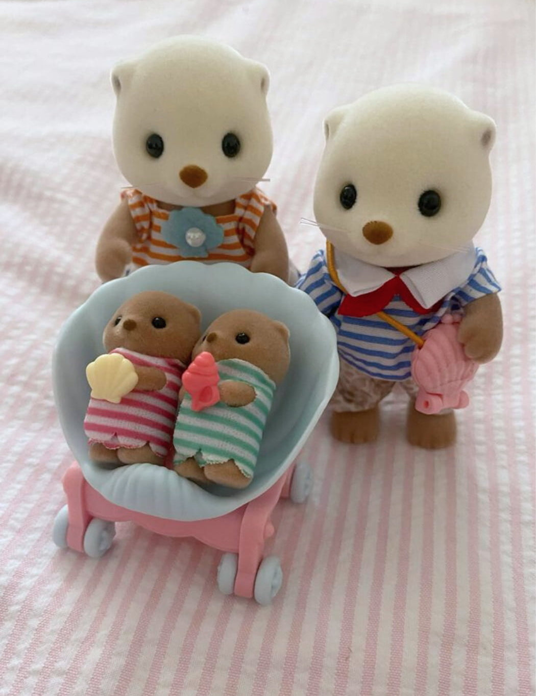 Two plush toy bears with a baby carriage on a pink striped background