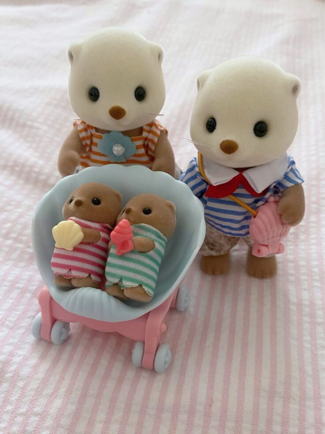 Two plush toy bears with a baby carriage on a pink striped background